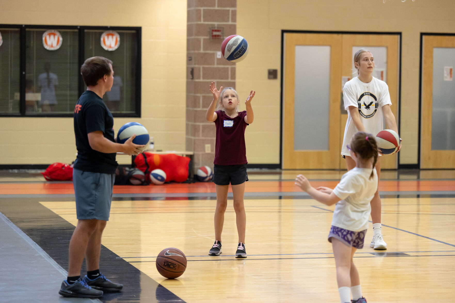 A young girl throws up a basketball while others look on