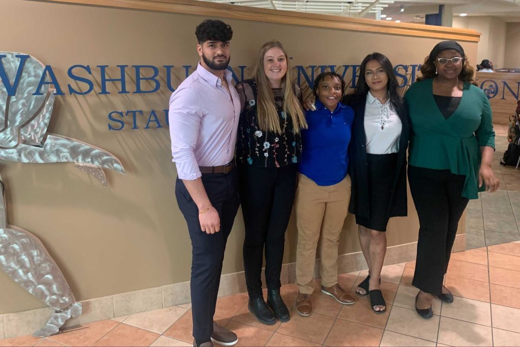 Mehrshad Bashang, Katelyn Eilders, Ja’Niya LaBeaux, Soniya Tamang and Aloaye Abdul Saliu stand in front of a Washburn University sign