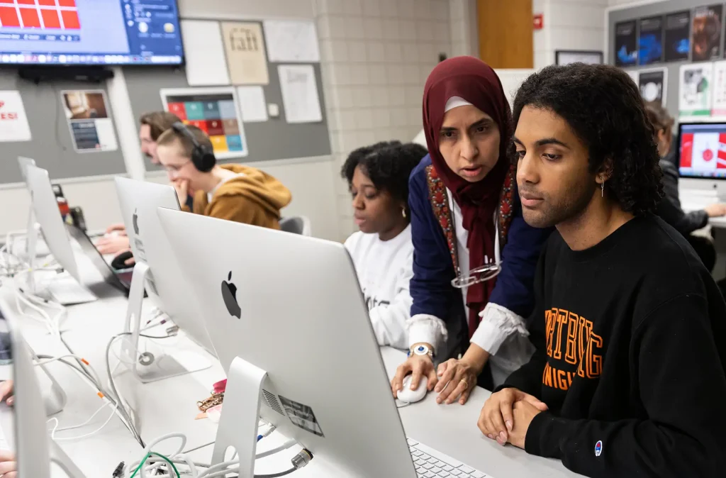 Graphic design professor helping student in the graphics lab