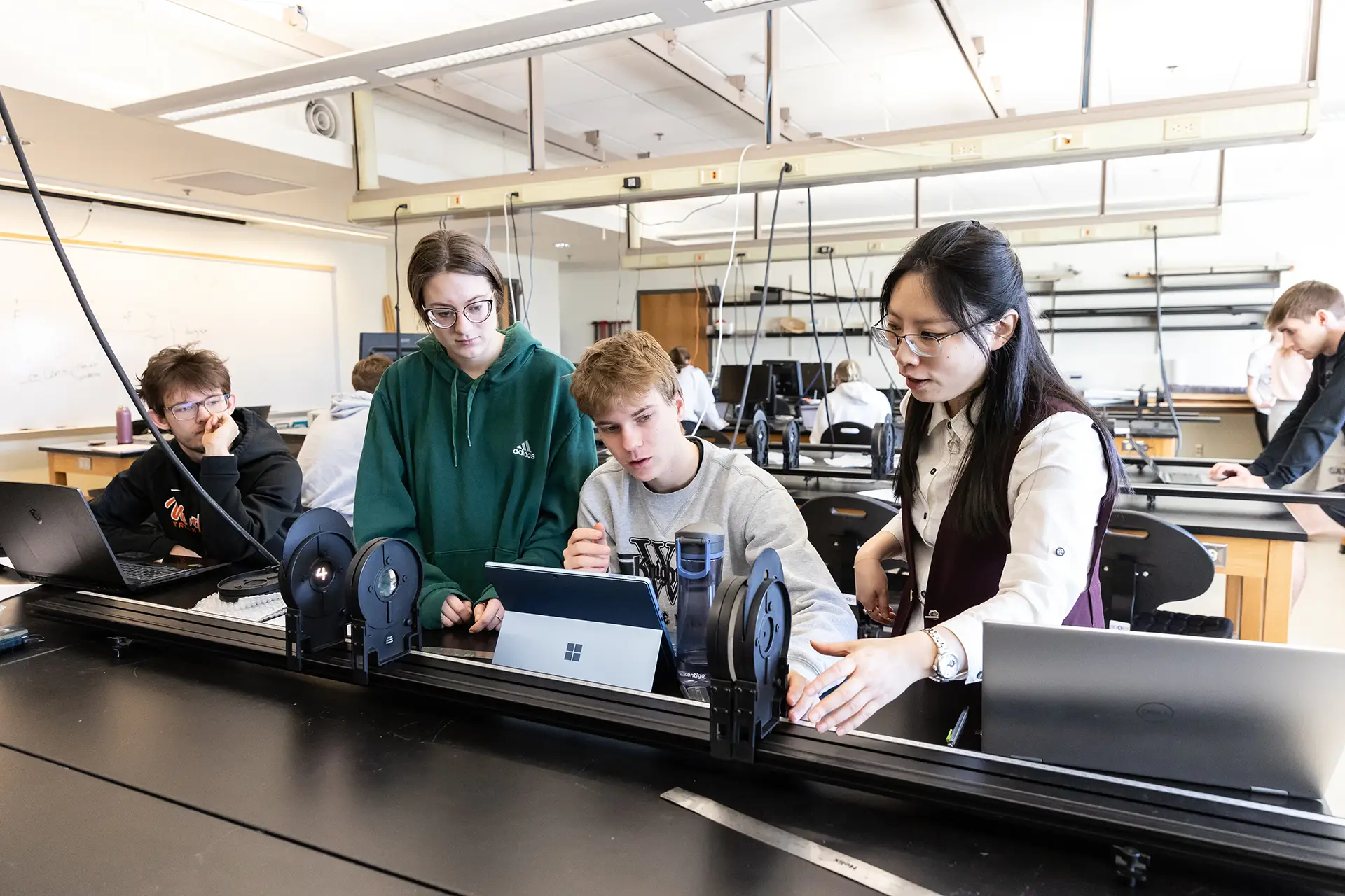 Professor helping students in a general physics lab