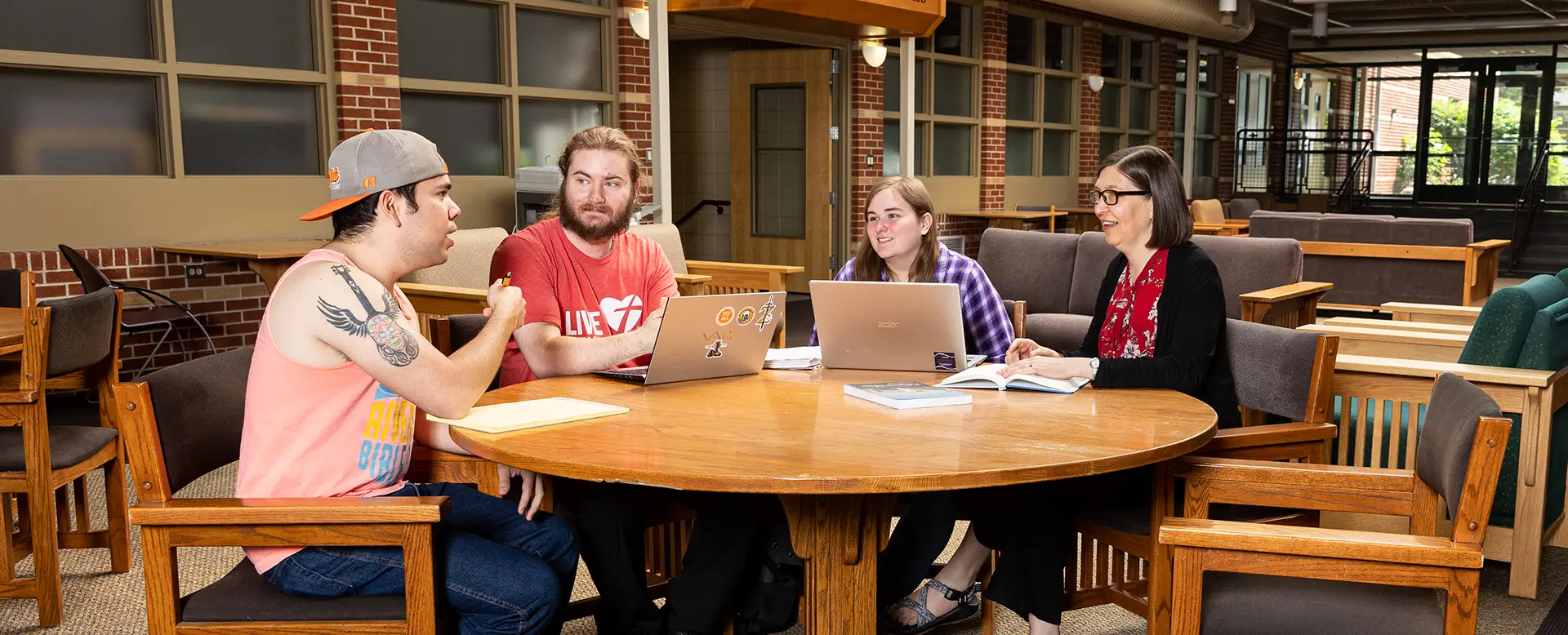 Religion professor having a discussion with students around a table in Cardinal Commons
