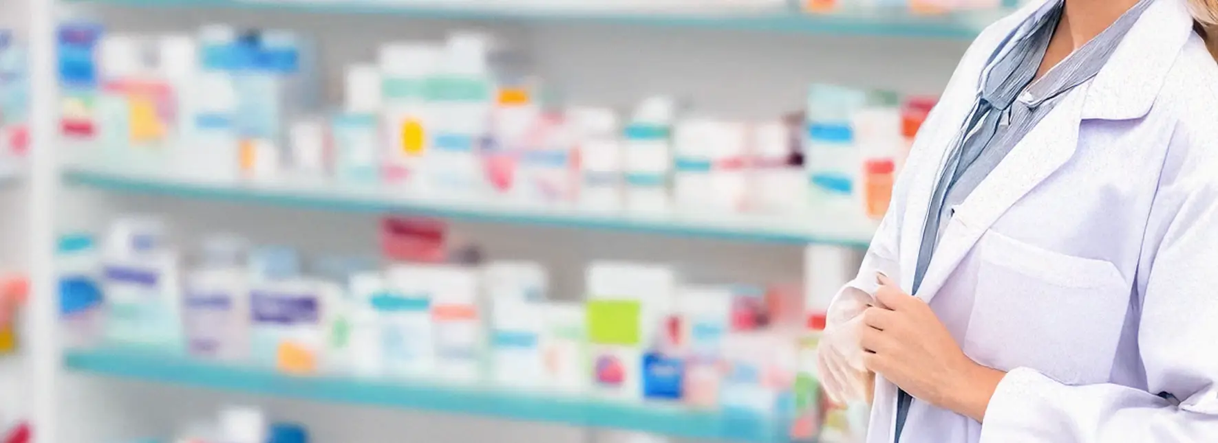 Pharmacist in the foreground with blurred pill boxes on shelves in the background