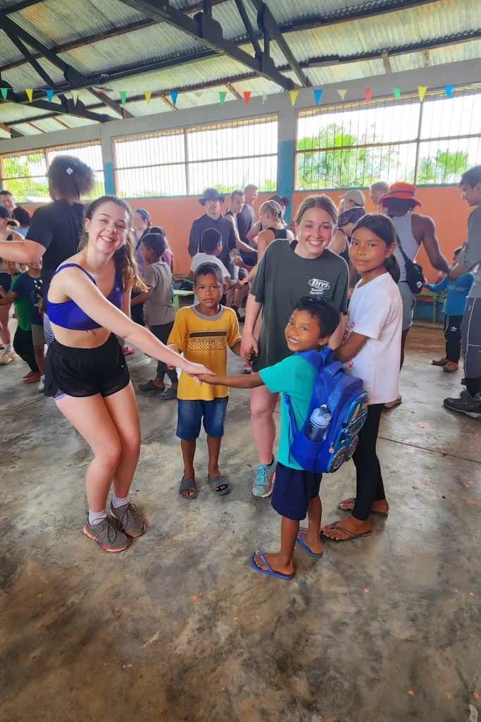 Wartburg students holding hands in a a circle with young children while studying abroad in their Amazonian Ecology and Culture II class