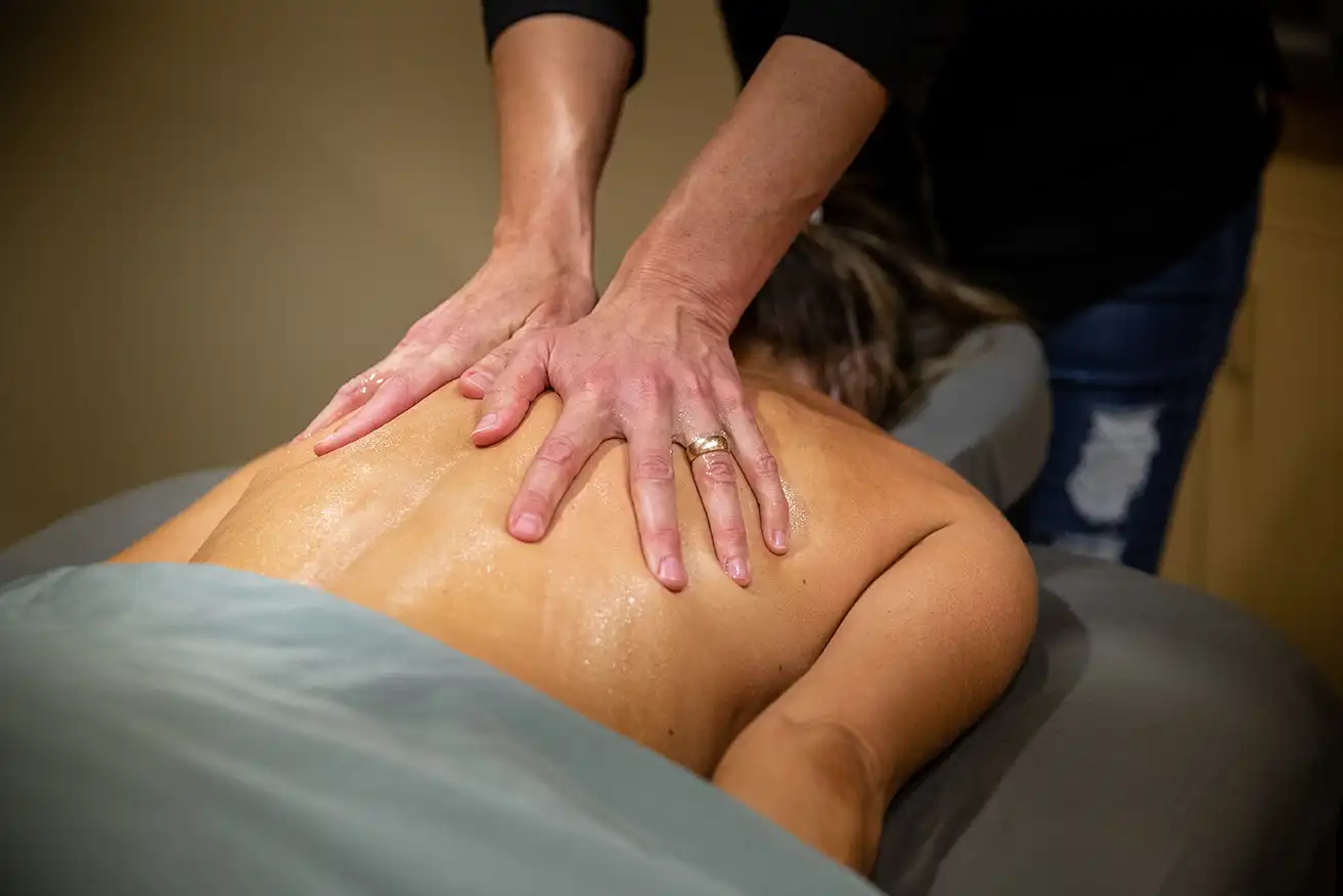 a therapist massages the top of a client's back