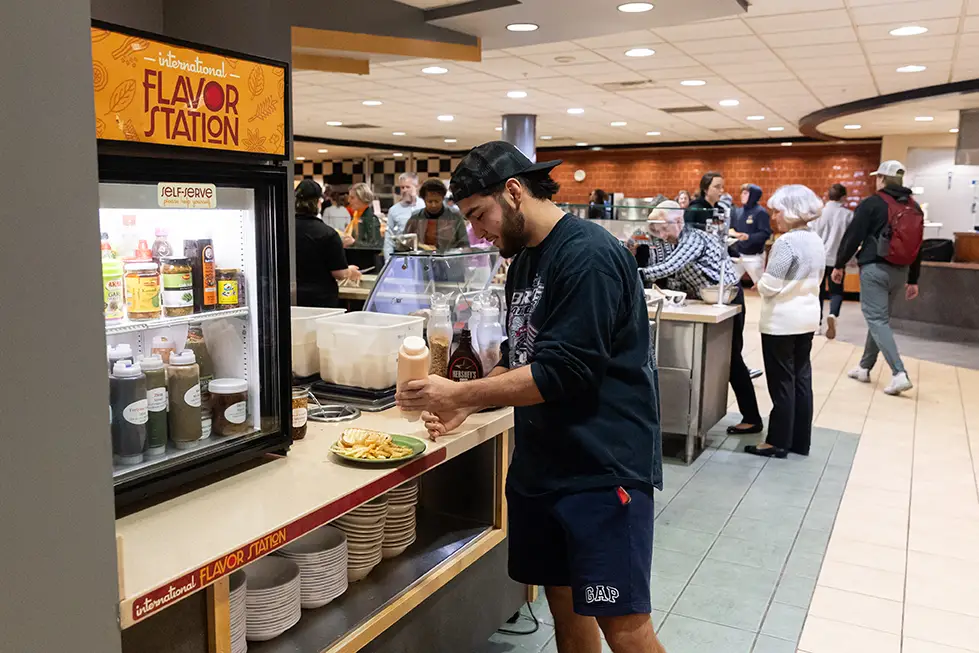 Mensa Flavor Station - student adding sauces to his meal