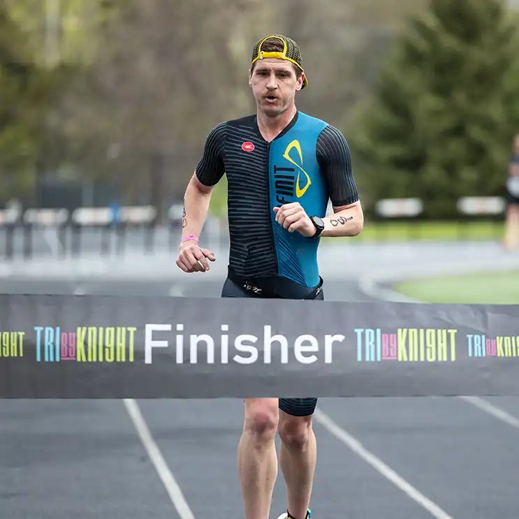 Man crosses the finish line at the TriByKnight