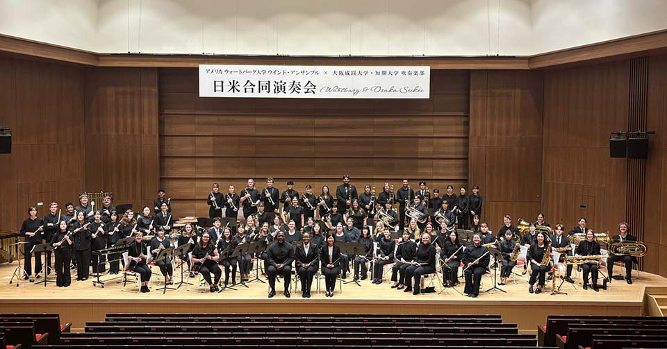 Wind Ensemble poses on stage in Japan with Japenese performers
