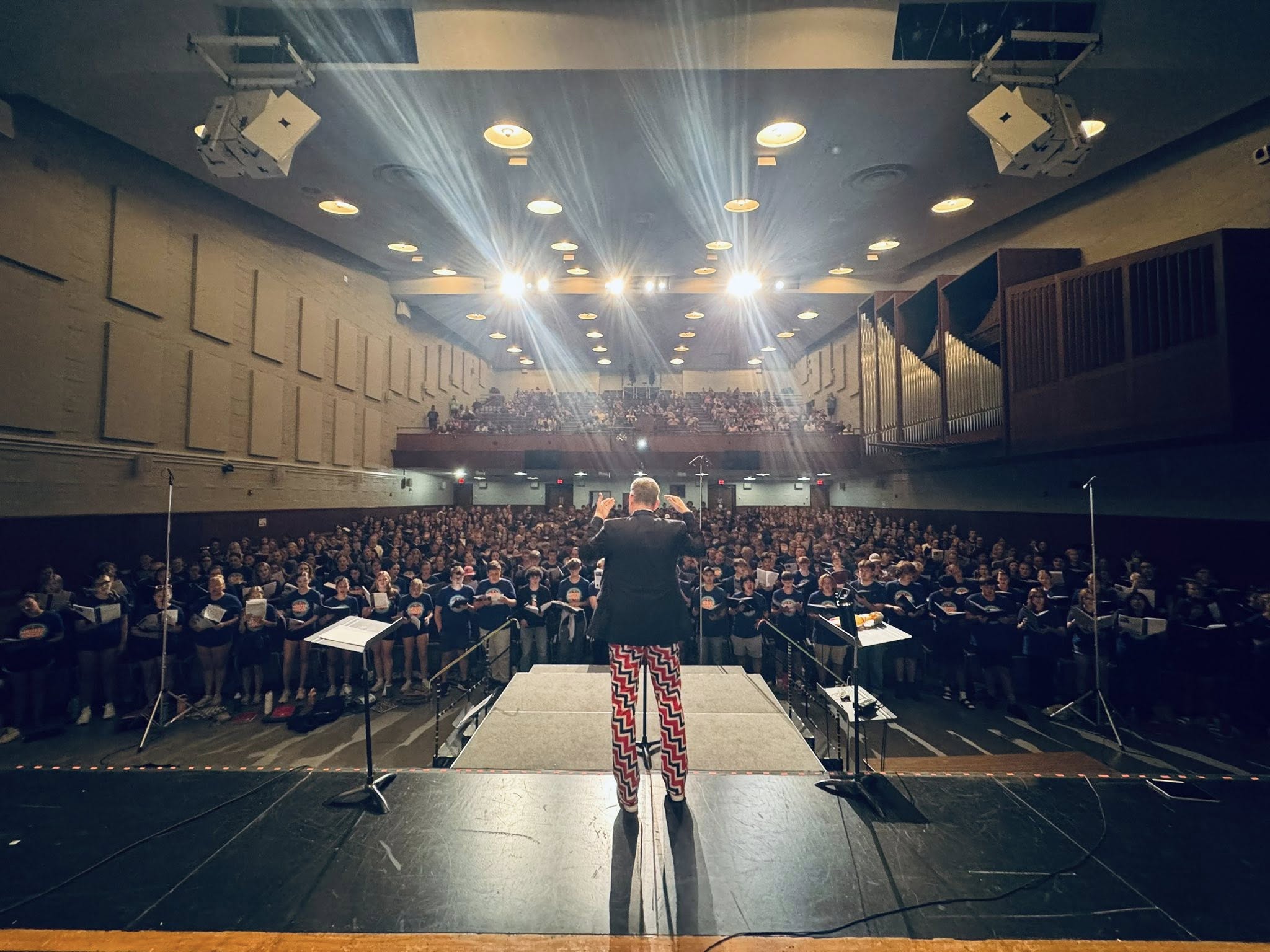All State Camp - dramatic shot of Dr. Nelson conducting in Neumann Auditorium in his Norwegian curling pants