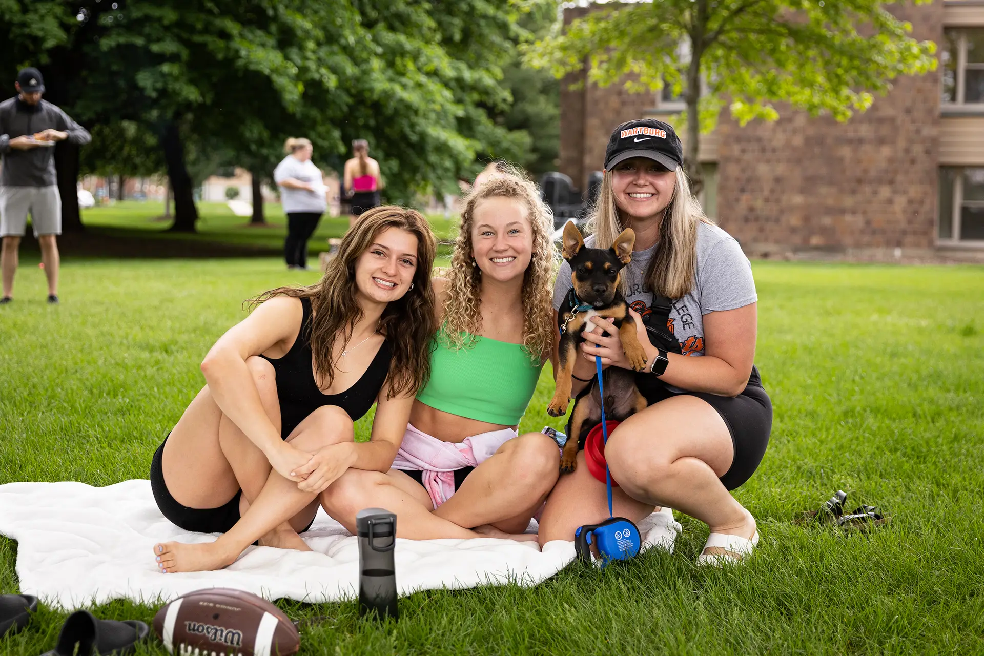 Students sitting on a blanket with a dog at Burgapalooza