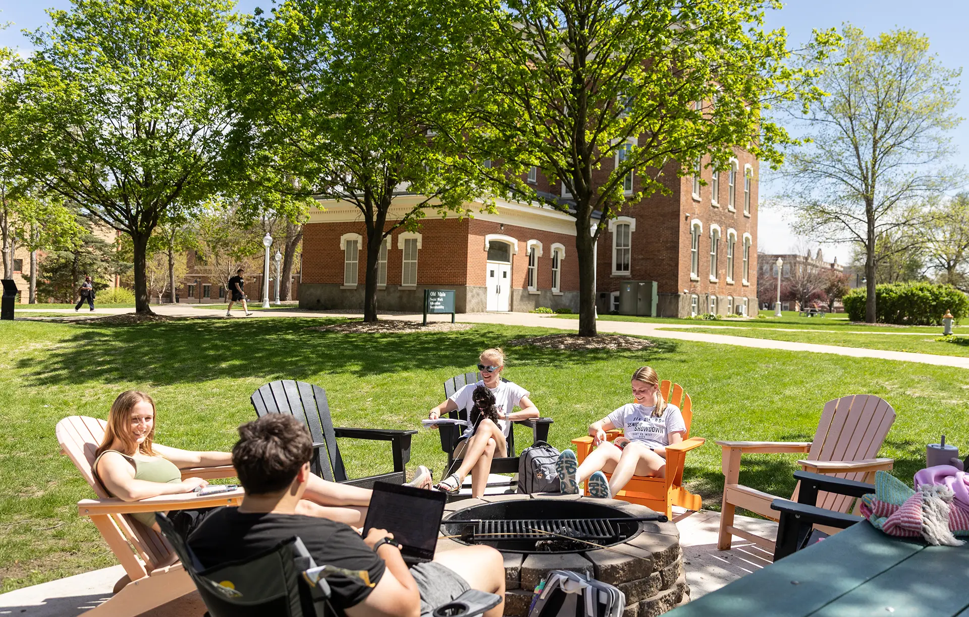 Students at a fire pit with Old Main in the background