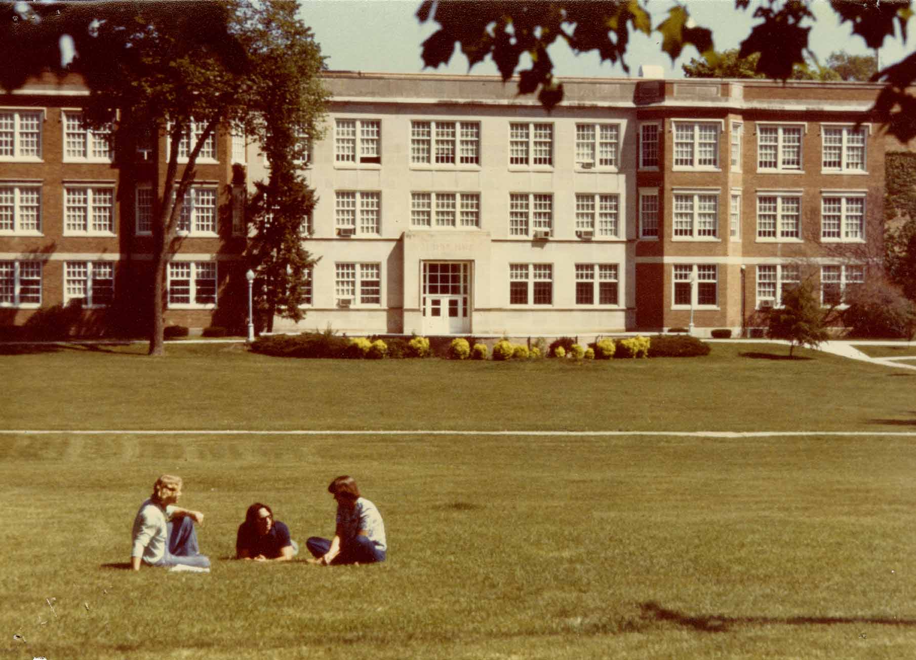 Students sit on the lawn outside Luther Hall circa 1979