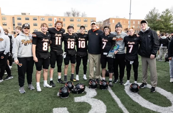 Members of the football team, including Riley Richards, and Coach Chris Winter gather for a photo after a game.