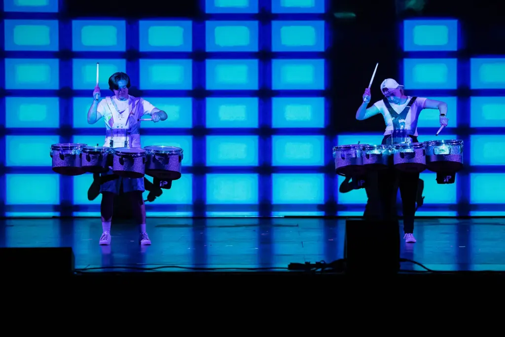 Two drummers play on a stage with a vivid blue background during Kastle Kapers.