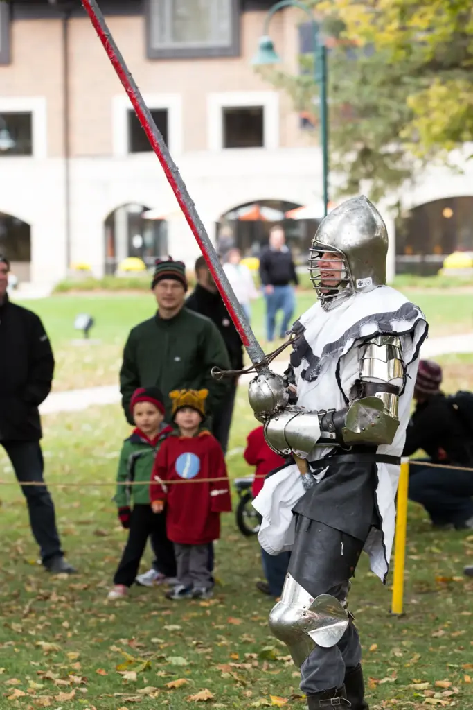A man in silver armor holds a long papier-mache sword during the Renaissance Faire.