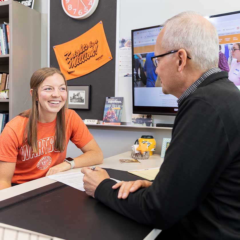 Kali Nelson sits across from Derek Solheim at his desk. 