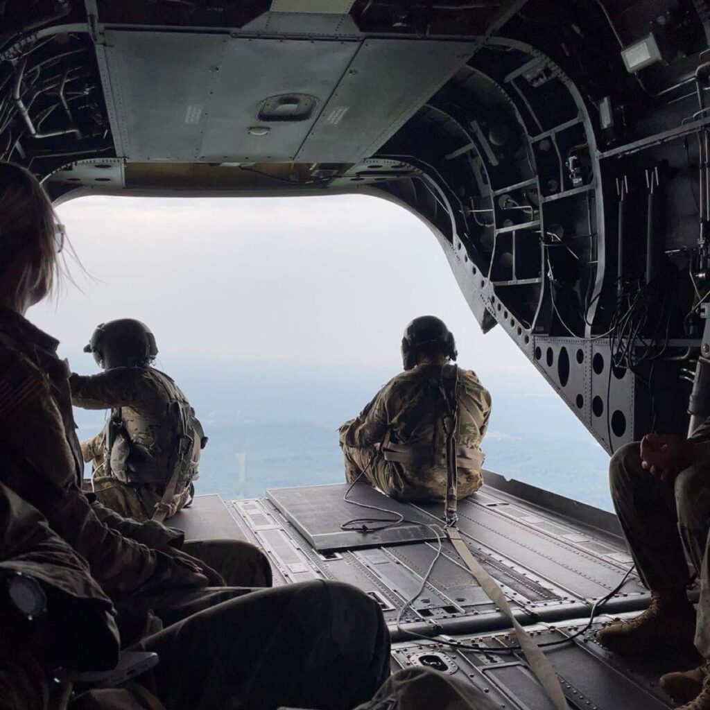 Alexa Melcher sits on the back of an open plane while it is flying.