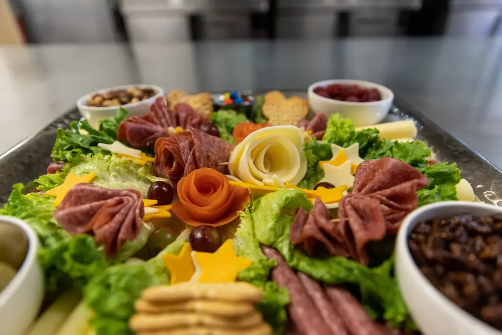 A charcuterie board from Wartburg Catering, featuring a variety of meats, cheeses, crackers, and other snacks.