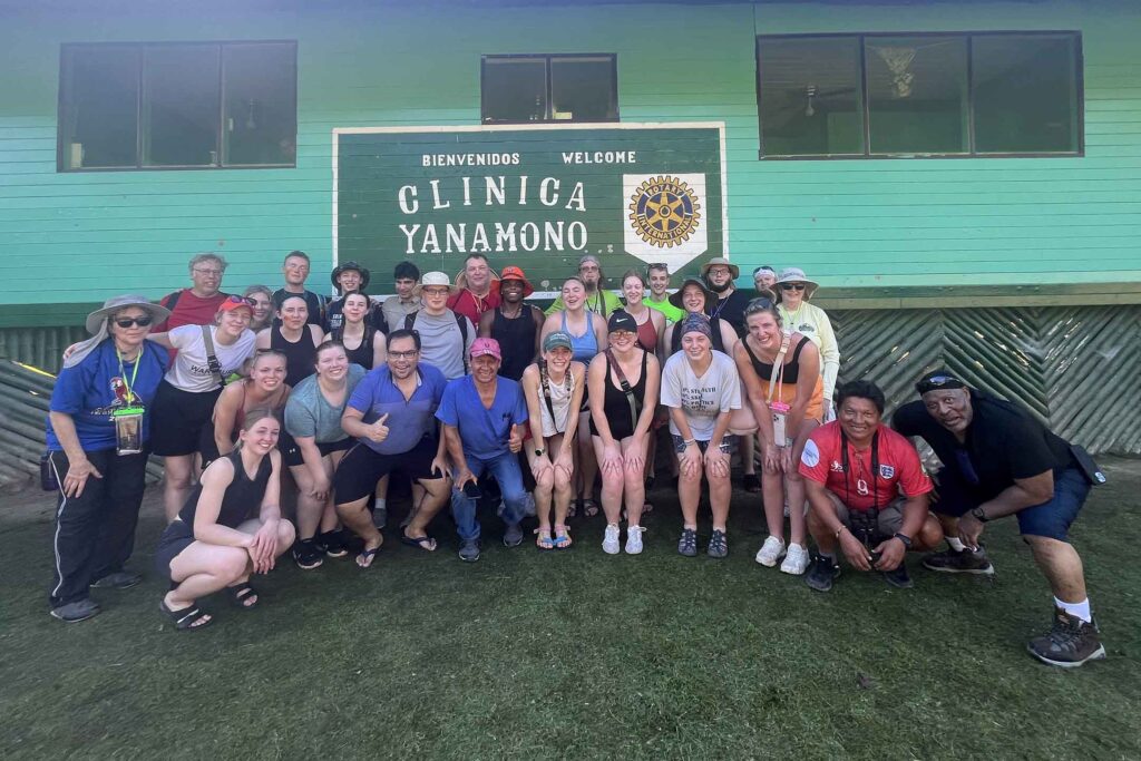 A group of Wartburg students pose in front of an aquamarine colored building in Peru. 