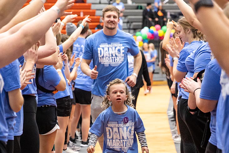 Owen Grover walks behind a young person under an archway of arms at a Dance Marathon celebration. 