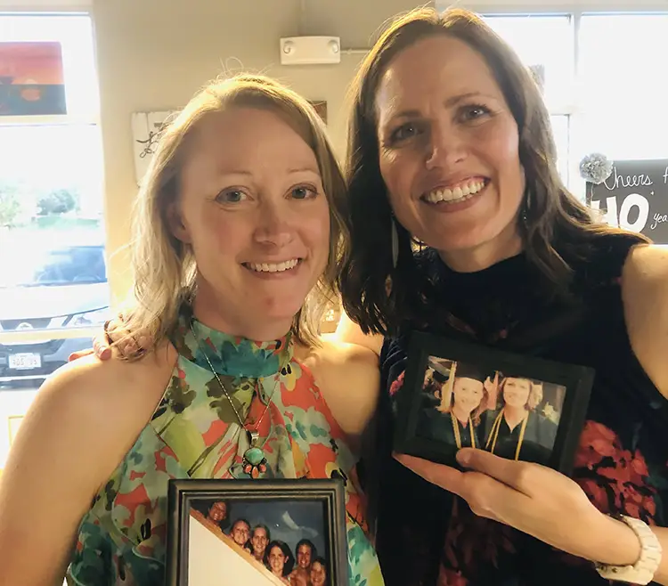 Keri and Jenni holding their graduation photos years later