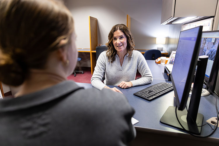 ARC staff member talking with student at a computer station