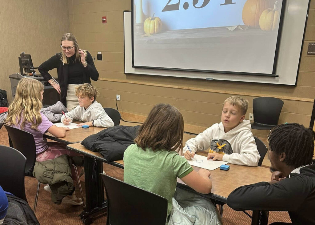 Middle School students sit at tables in pairs while Wartburg students lead them through an exercise