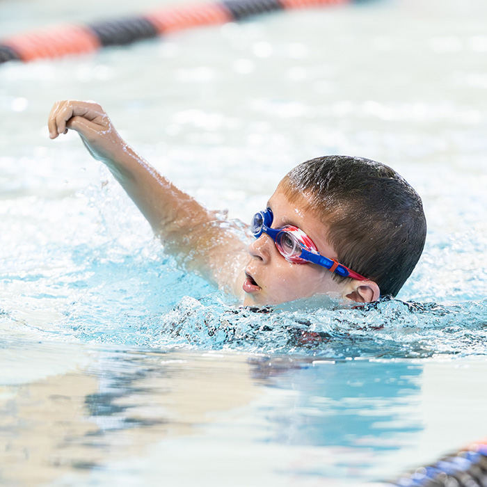 Young boy in goggles swimming