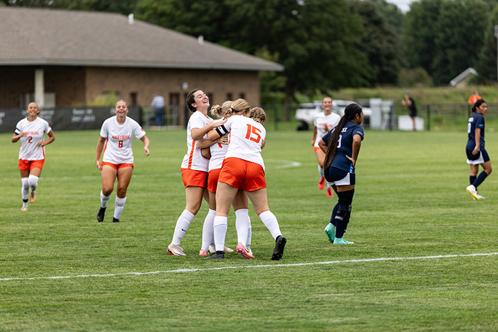 Women's soccer players celebrate on the field.