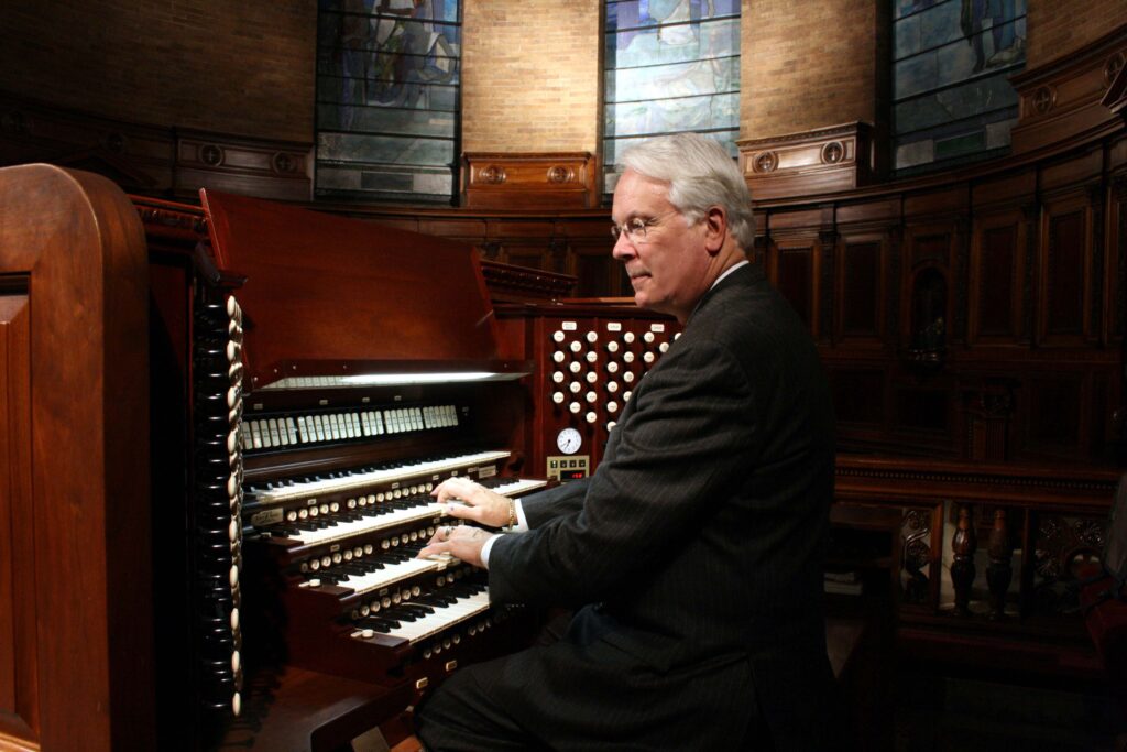 Stephen Hamilton sits at an organ with his fingers on the keyboard.