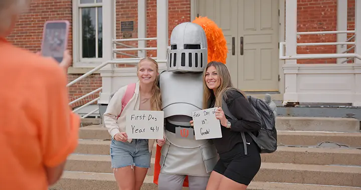Two students pose with Sir Victor in front of Old Main for their first-day-of-school photo.