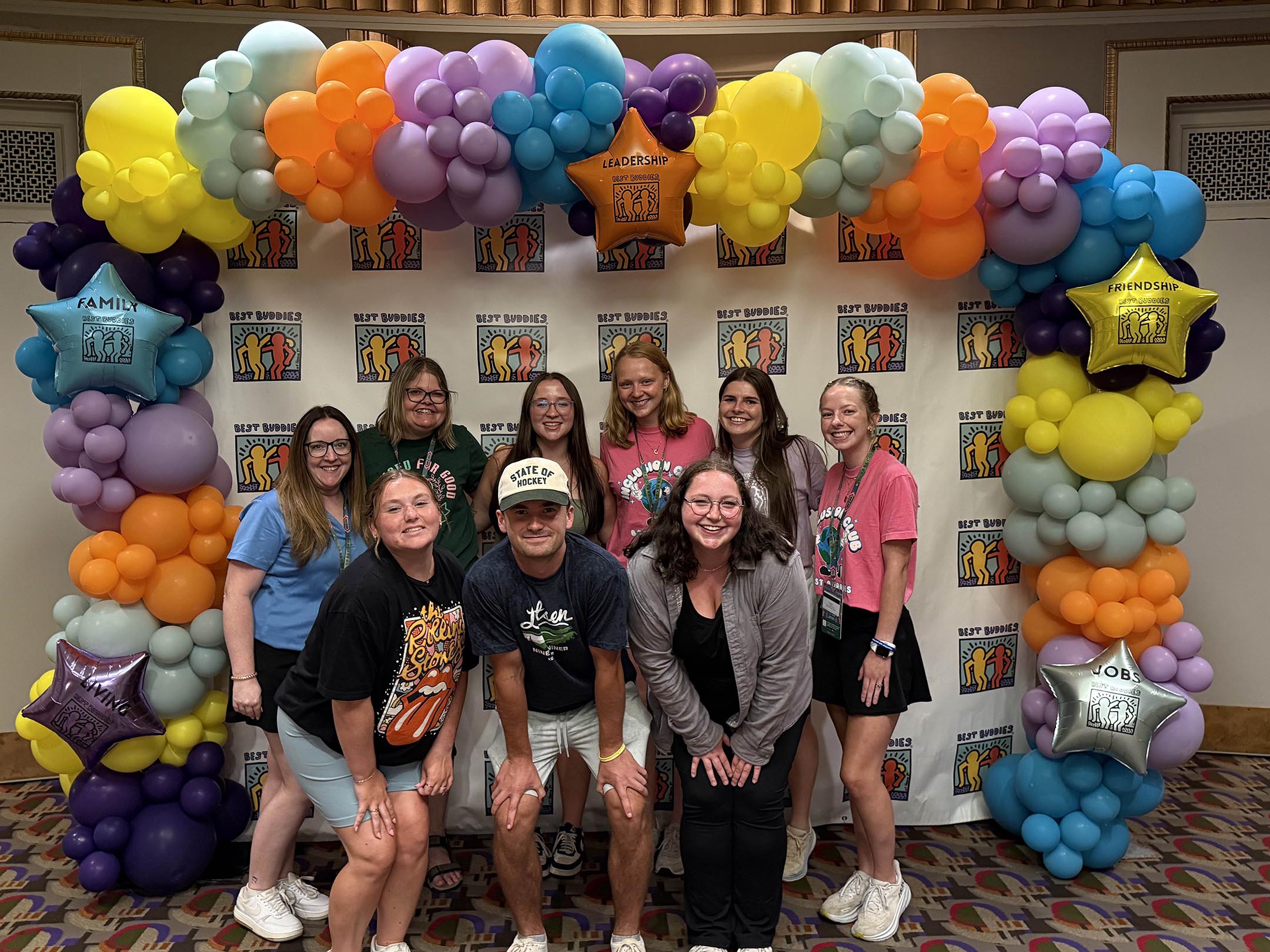 Jack Crane stands with other students in front of a Best Buddies background
